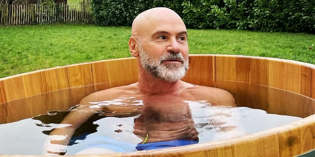 Neil in a wooden barrel cold tub in the garden, water steaming around him